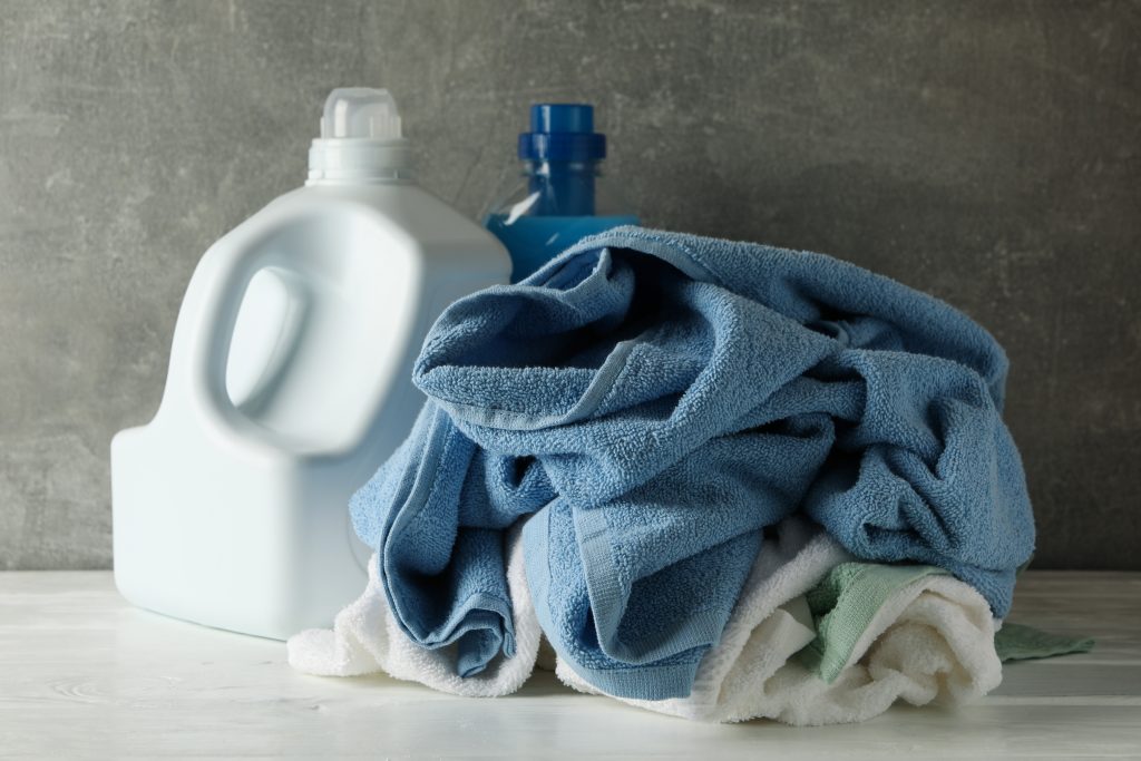 Detergent and crumpled towels against gray background