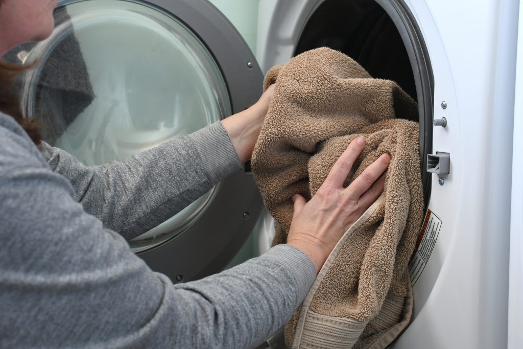 Woman putting towels in washer to get rid of towel smell