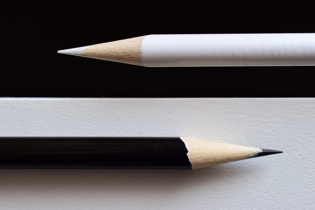 Black pencil on white background and white pencil on black background