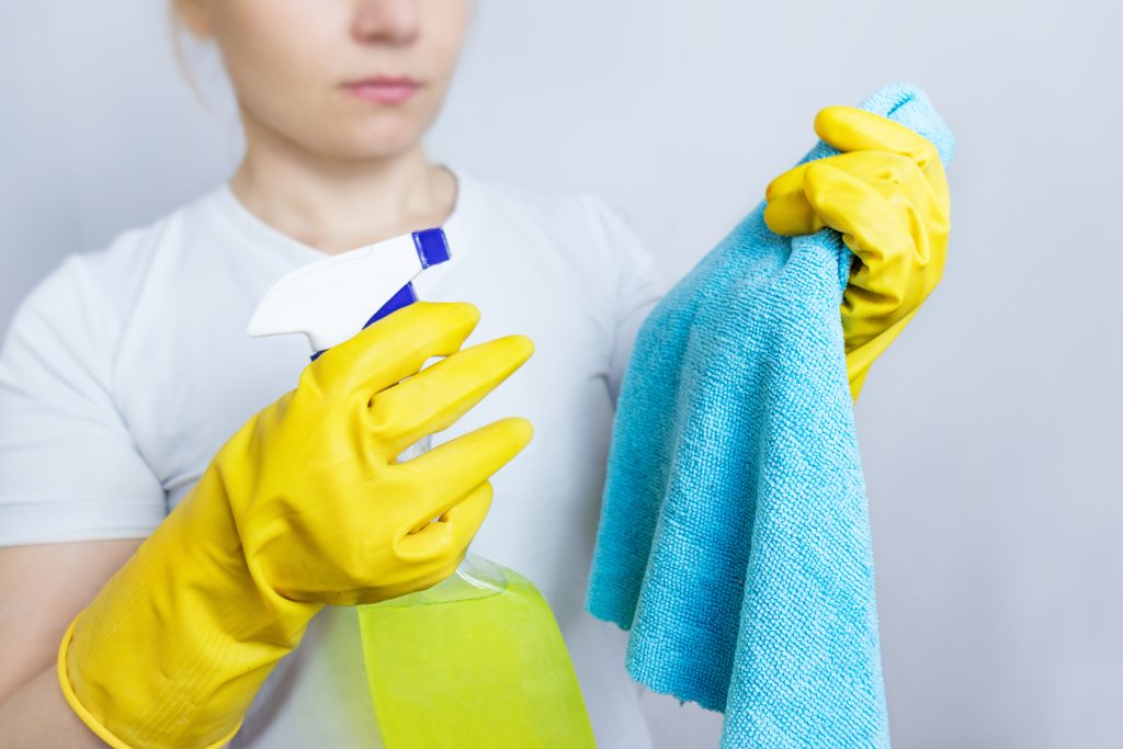 A woman holding a cleaning rag and glass cleaner