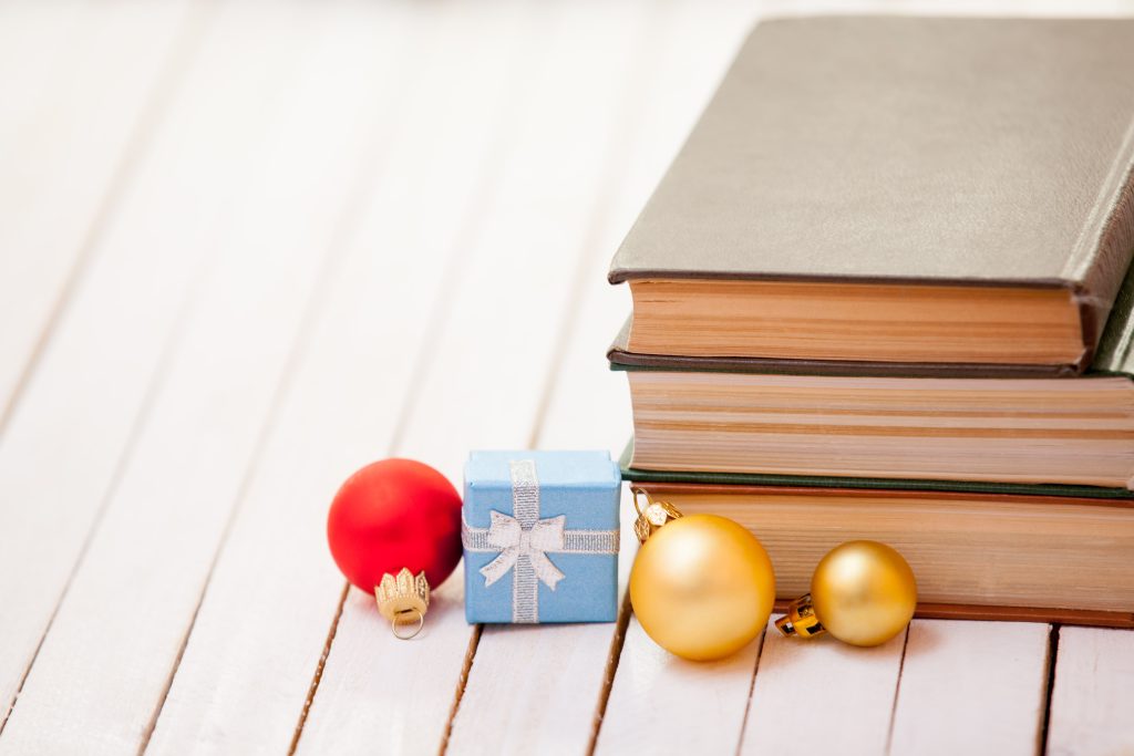 Stacked books and Christmas ornaments on a wooden table