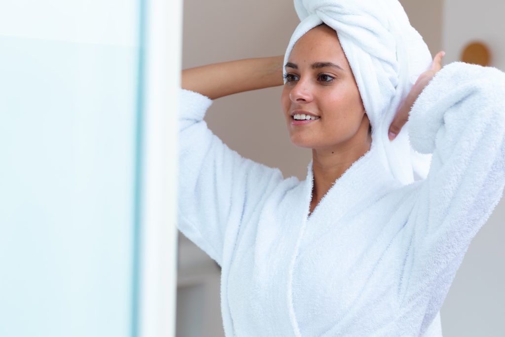 A woman in a bathrobe looking in the mirror
