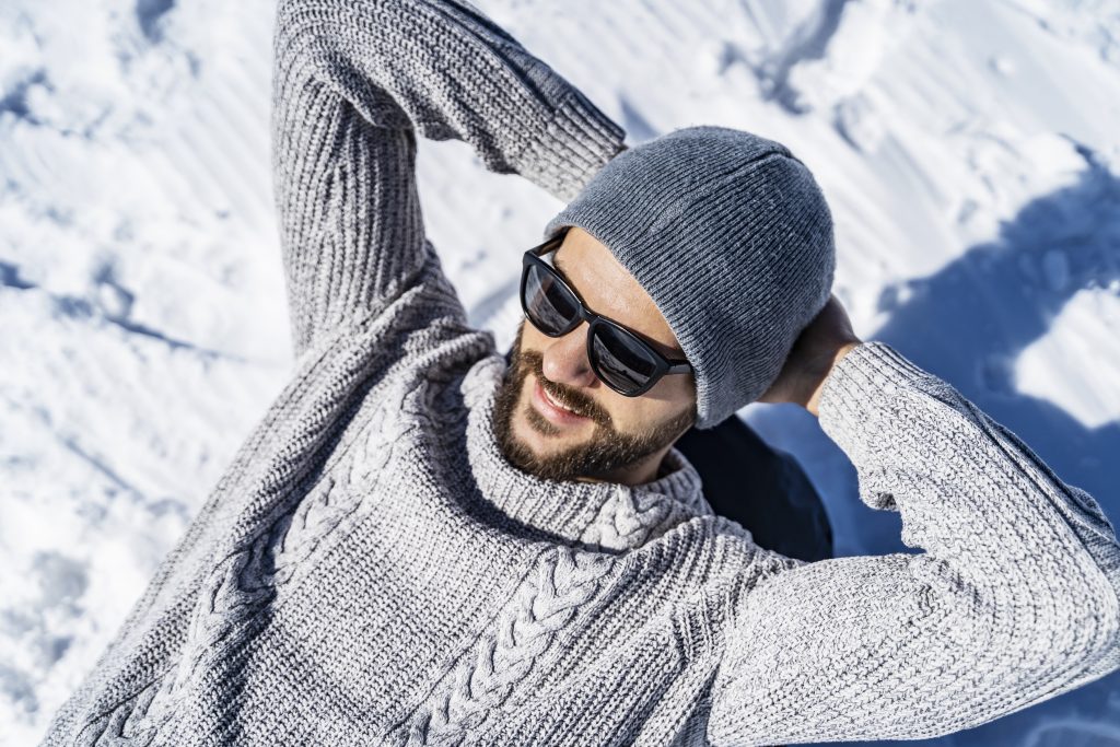 Man wearing a sweater and beanie relaxing outdoors