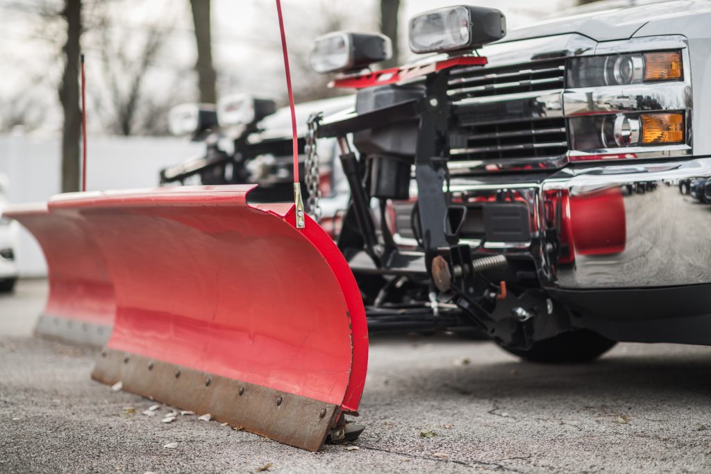 A truck with a red snow plow attached to the front